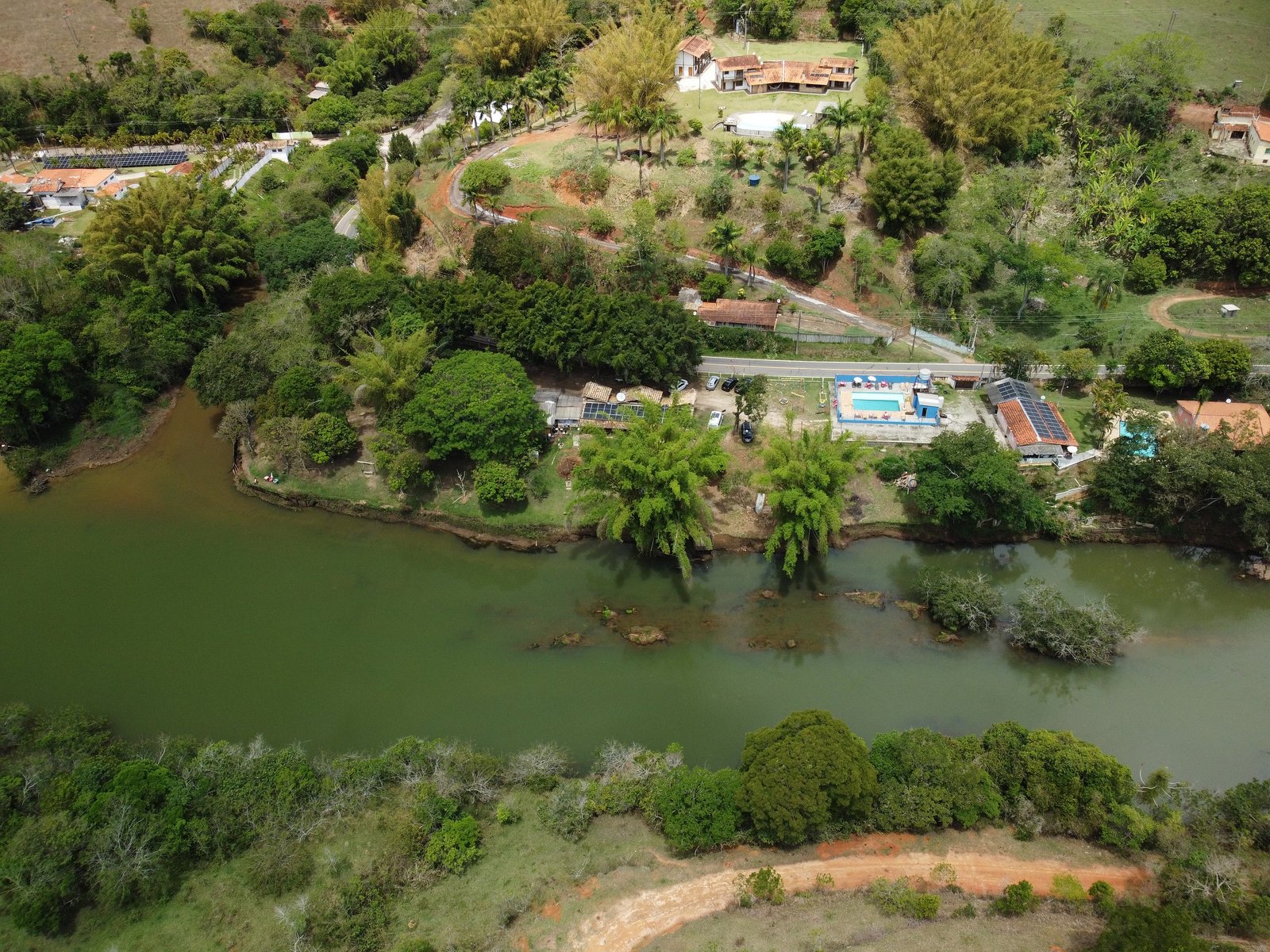Vista aérea do Mandizeiro: o Rio Paraíba do Sul verde-espelho cortando a mata, com a piscina e as casas da pousada na margem